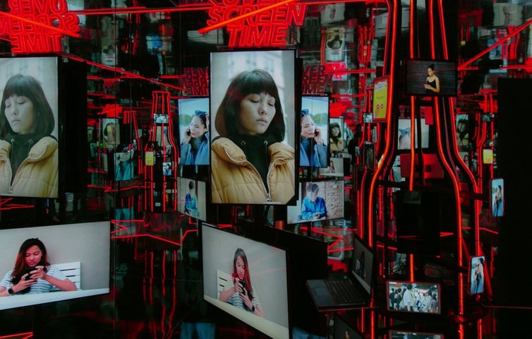 A dark red room lined with illuminated portrait screens