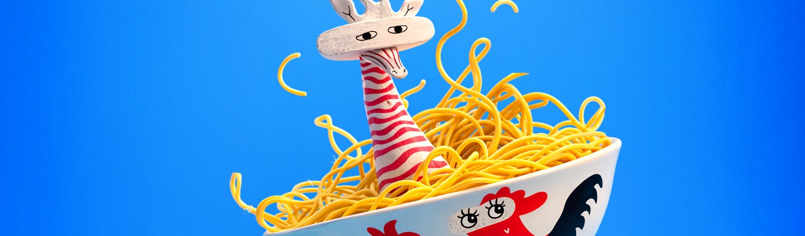 A noodle-bowl character sculpture on a blue background