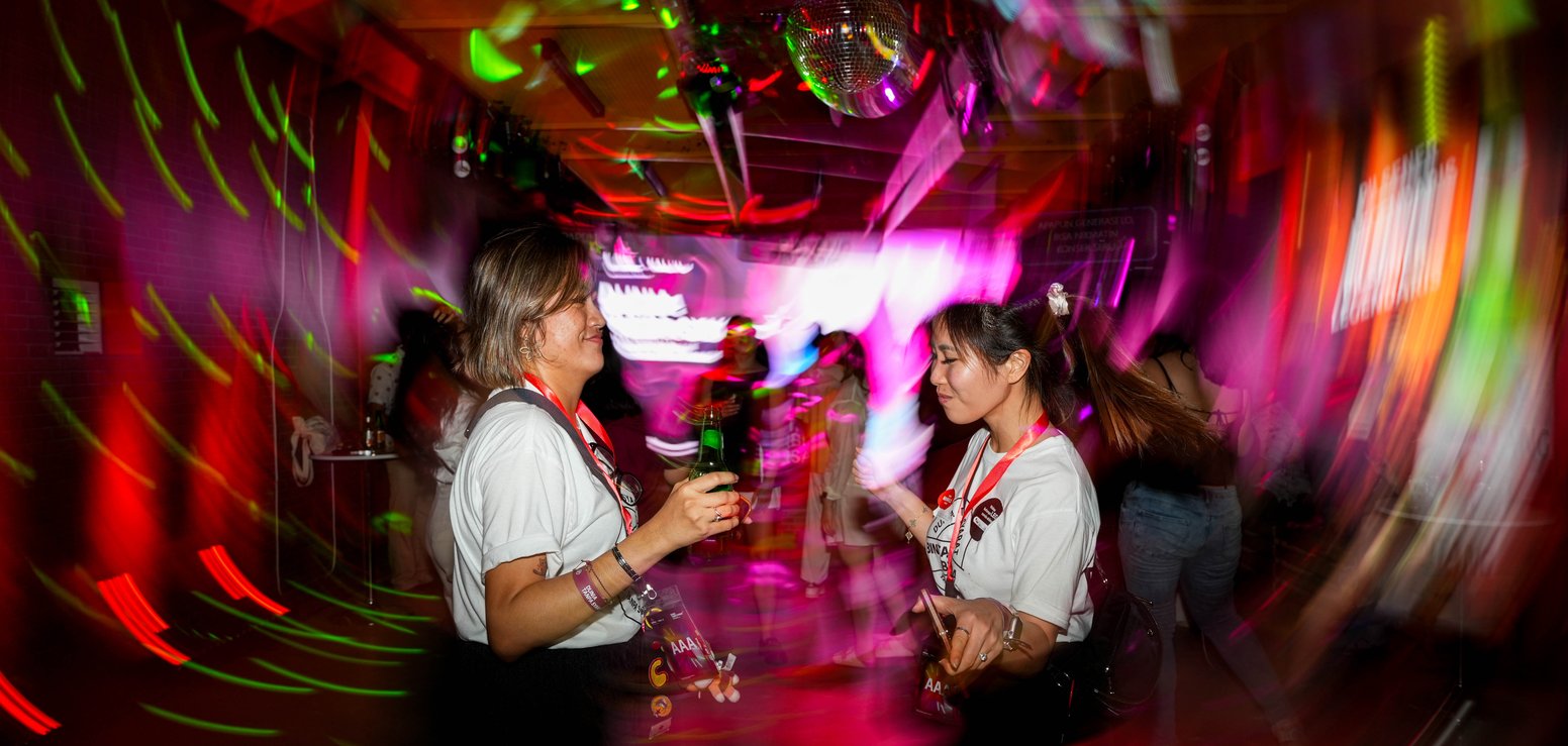Two visitors in a magenta-lit immersive space