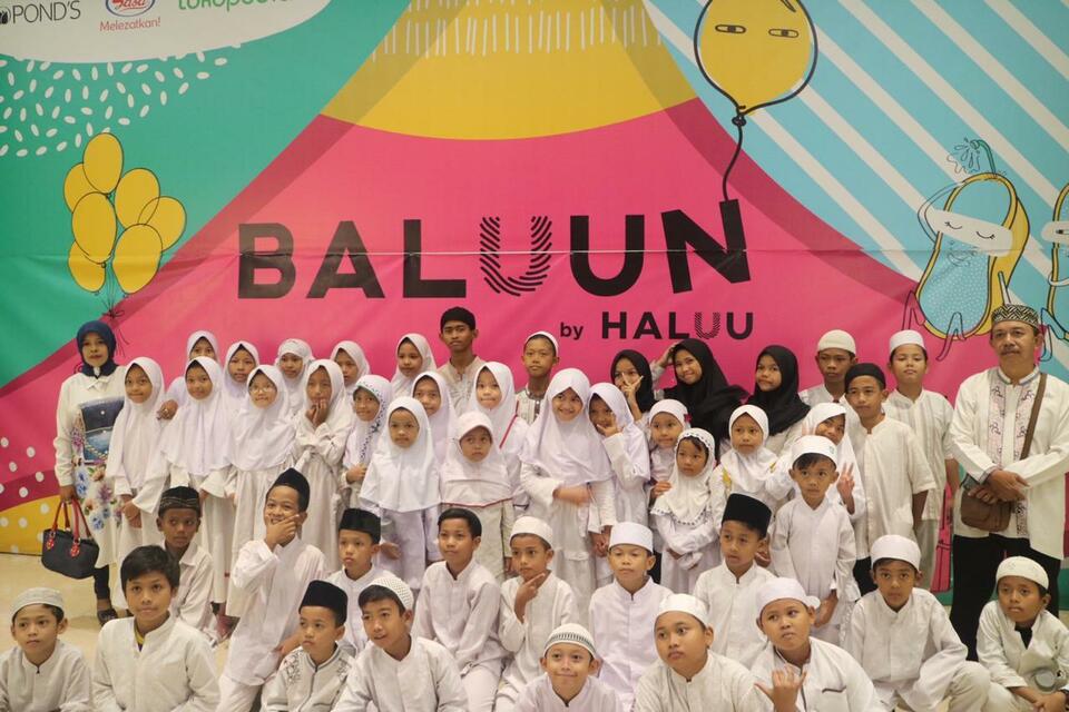 Schoolchildren in white uniforms posing in front of the Baluun by Haluu banner
