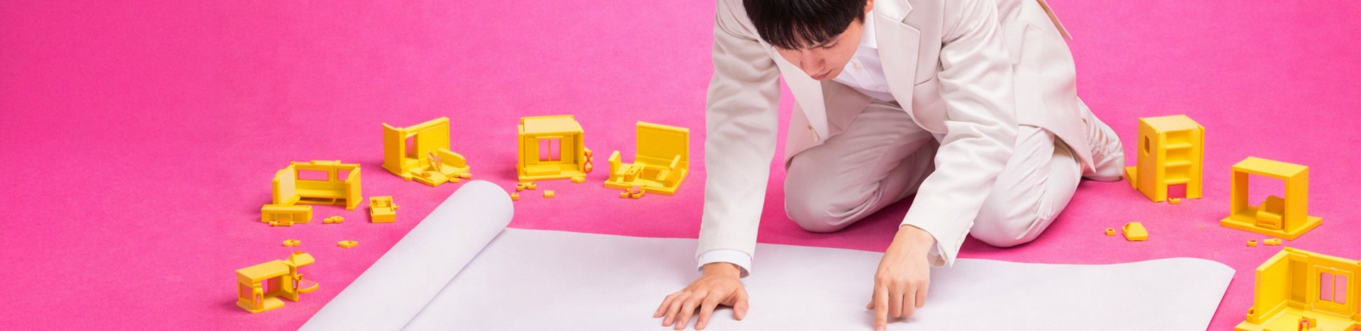 A performer reclining on a pink set scattered with small yellow figures