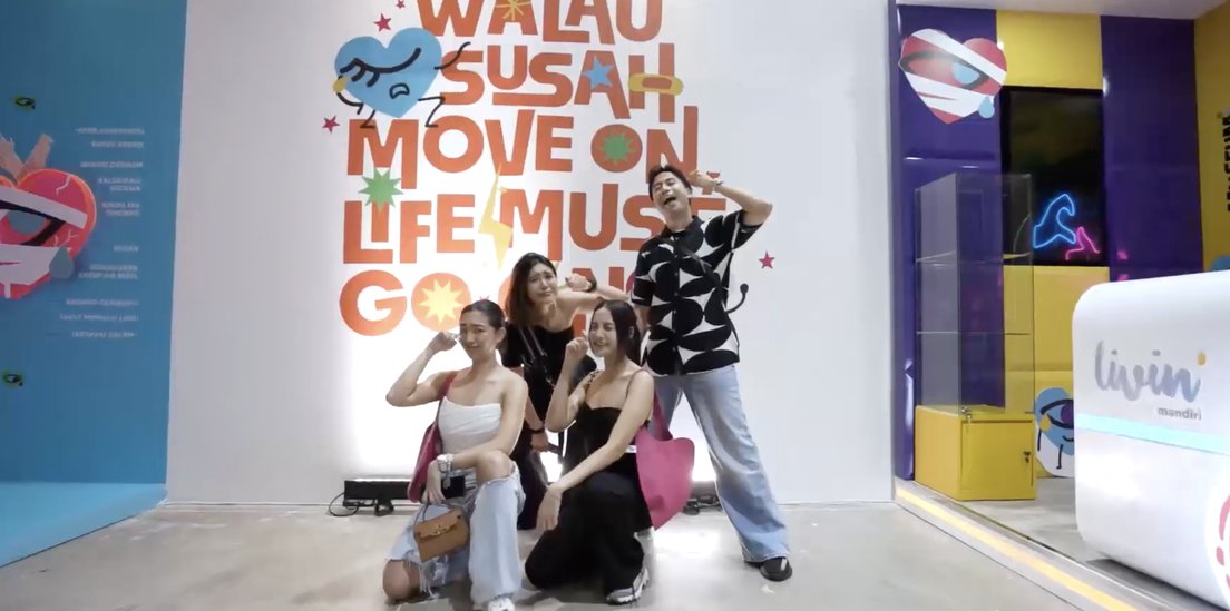 Visitors posing in front of a mural about moving on