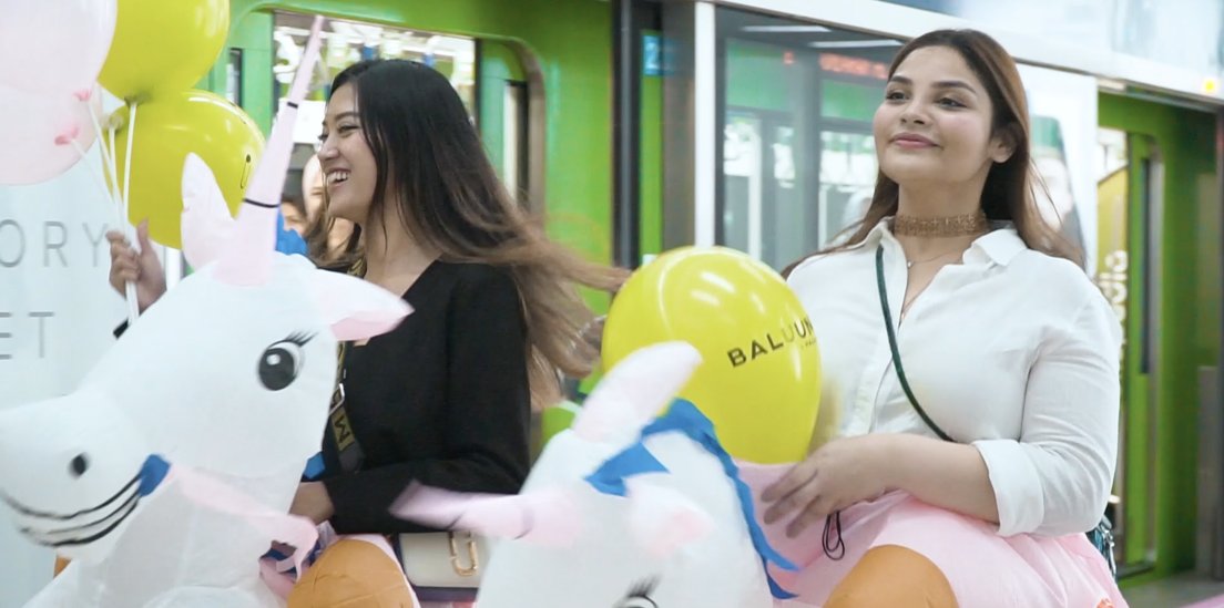Two visitors with an inflatable unicorn at the exhibition