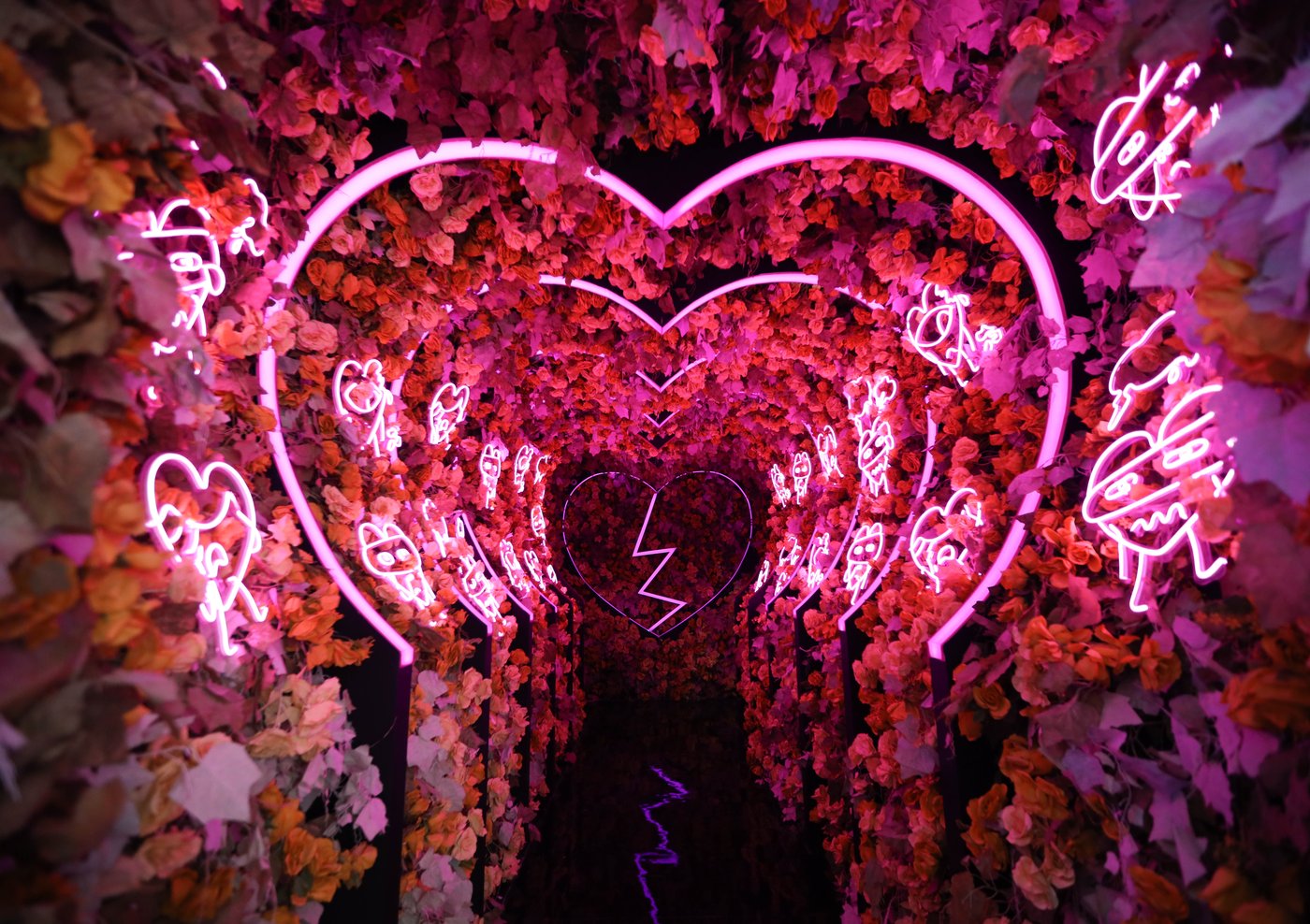 Neon heart tunnel lined with flowers inside Museum Patah Hati