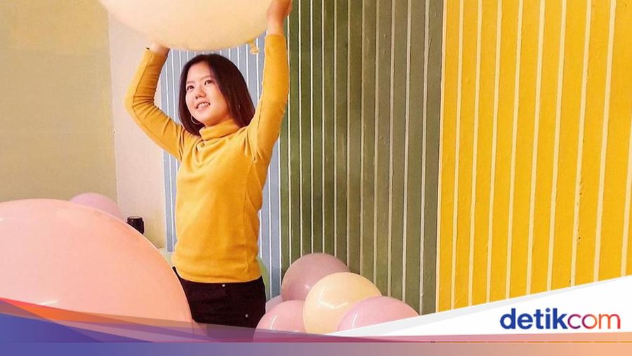 A visitor in a yellow top holding up a large pastel balloon at Baluun by HALUU